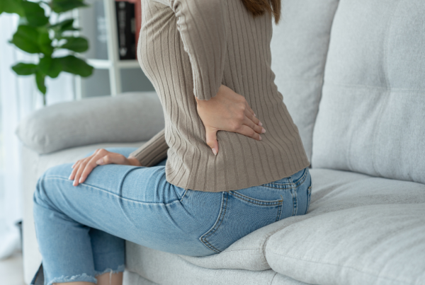 woman sitting on a couch holding her hip and lower back area