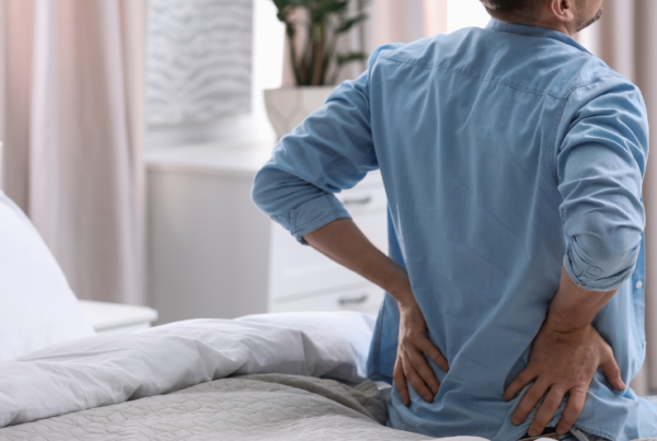 Person with tailbone pain holding their lower back while sitting