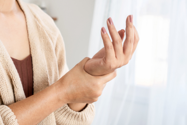 Person experiencing wrist pain holding their left wrist with their right hand