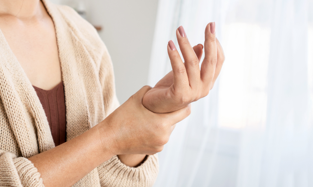 Person experiencing wrist pain holding their left wrist with their right hand