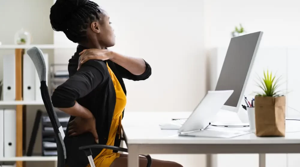 Woman experiencing thoracic back pain at work