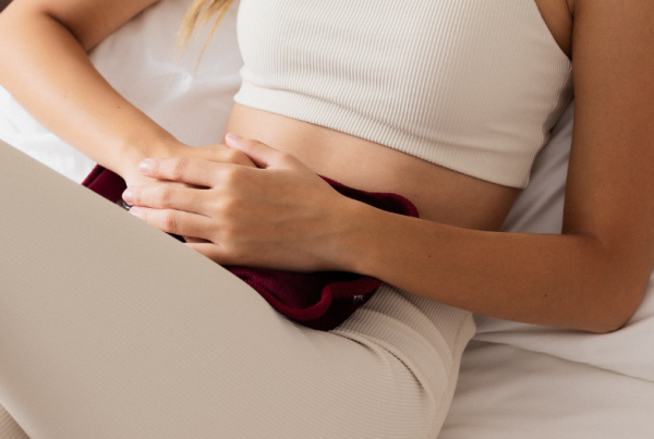 Person with adenomyosis laying down with a heated water bottle