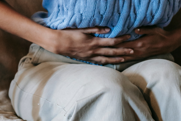 Person leaning over and holding their abdomen due to chronic pelvic pain