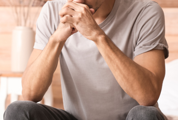 Person sitting alone and thinking with their hands clasped together