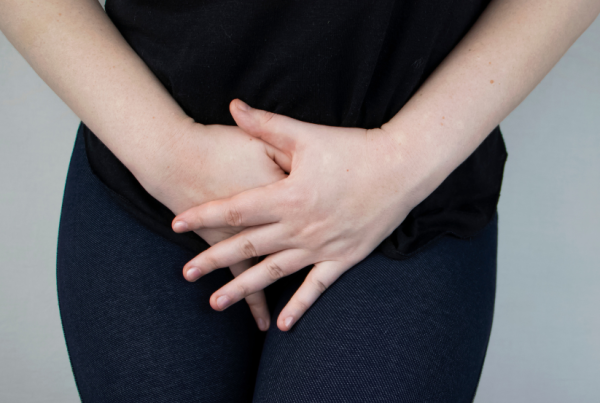 Person holding or covering their lower pelvic area with both hands