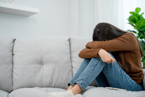 Upset woman sitting on a couch with her head on her knees