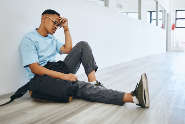 Person sitting alone on the floor of a hallway looking frustrated