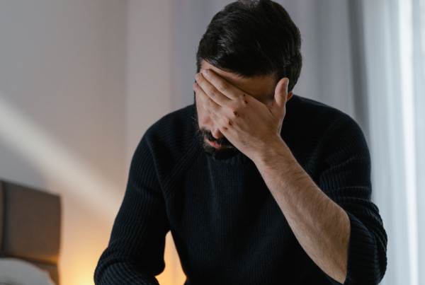 man sitting with his hand to his face in frustration