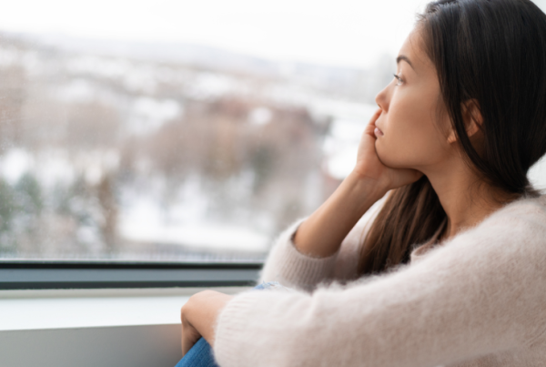 Person sorrowfully looking out of a window