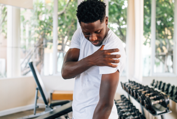 Man in a weight lifting room holding his shoulder