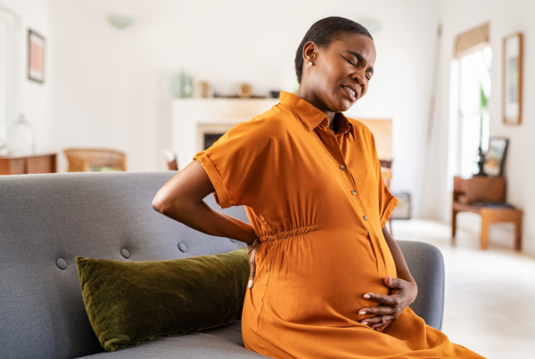 Pregnant woman sitting on a couch in pain
