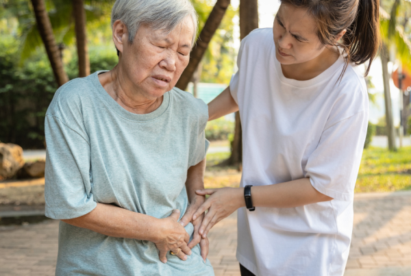 Person assisting an older individual who is experiencing hip pain