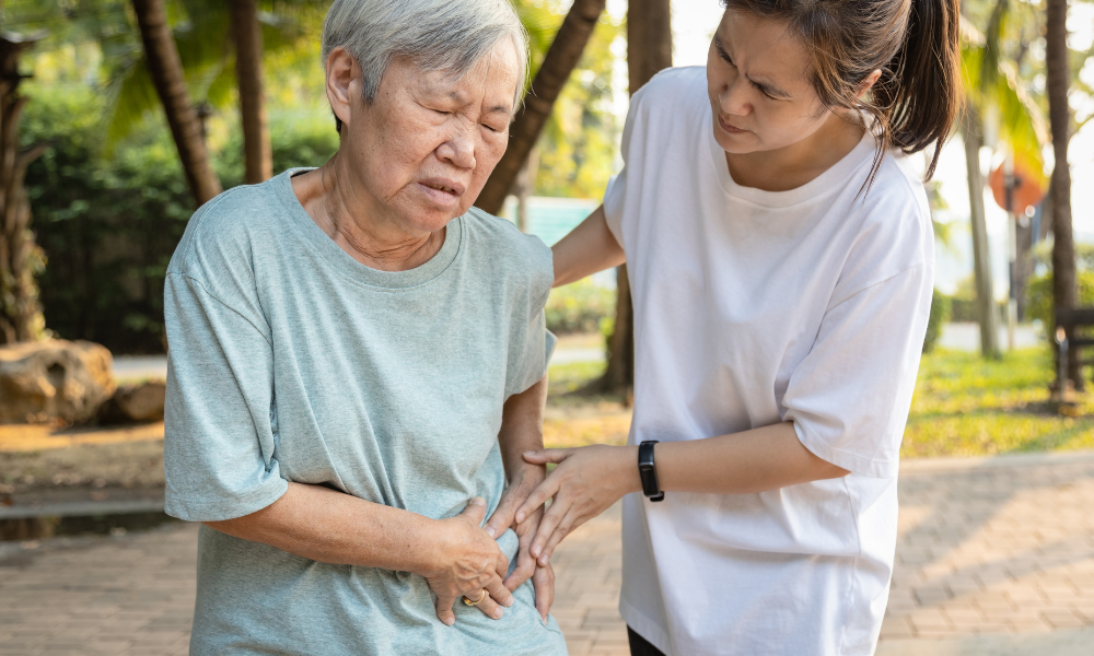 Person assisting an older individual who is experiencing hip pain