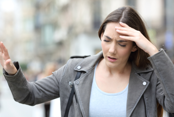 woman walking in the street while looking dizzy and disoriented